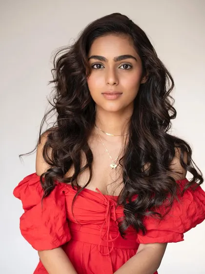 A serene portrait of the model in the red dress. Her dewy makeup and soft, voluminous curls give her a romantic and approachable look.