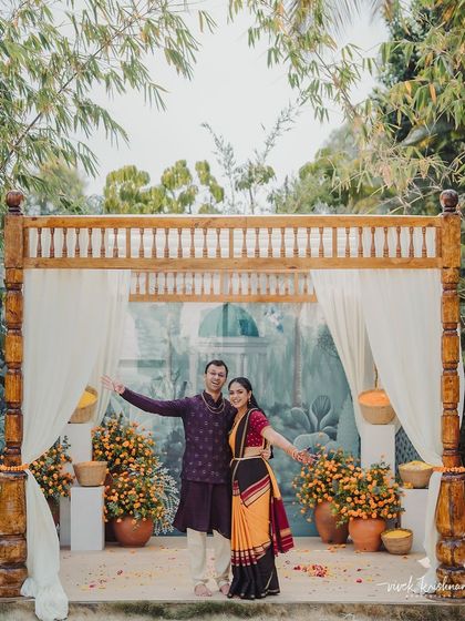 The happy couple poses at their Varapuja ceremony, framed by the simple wooden mandap and a beautiful hand-painted backdrop.