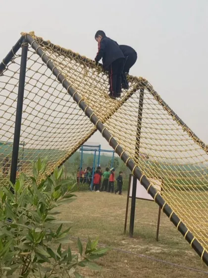 Students work together to climb a net structure at Victory Adventure Camp. This activity promotes teamwork and encourages peers to support each other in overcoming challenges.