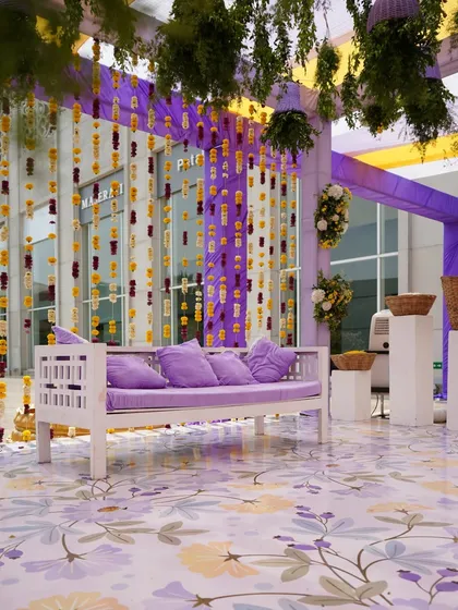 For a modern Mehendi, I designed this seating area with a lavender and yellow color scheme. The floral-patterned floor and hanging marigold strings create a fresh and stylish look.