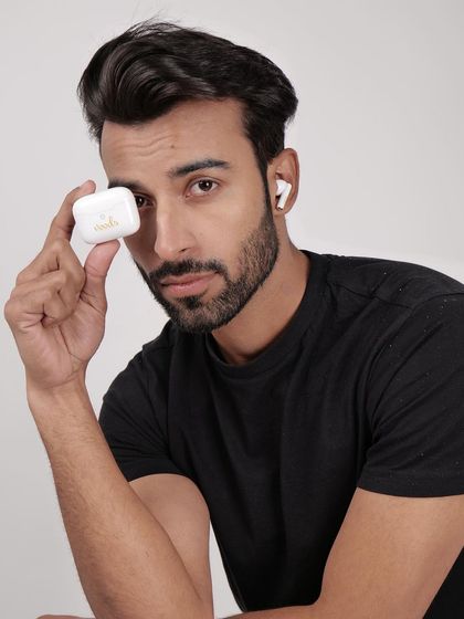 A model holding a white earbud case, with one earbud in his ear. This shot clearly displays the product and its charging case in a relatable human context.