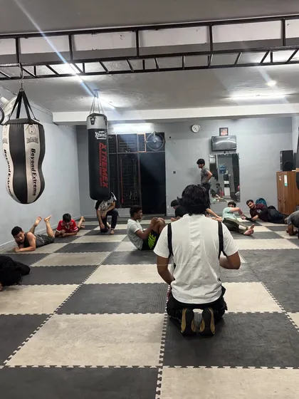 A view of our group core conditioning workout. I lead the session from the front, guiding students through various abdominal exercises on the matted floor, with punching bags ready for the next phase of training.