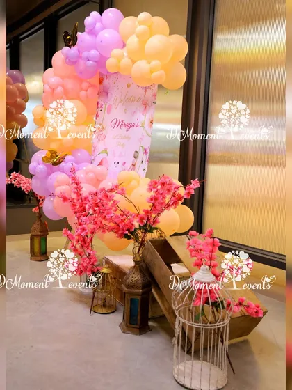 A whimsical party setup featuring pastel balloons, cherry blossom branches, and decorative bird cages. This unique combination creates a soft and dreamy atmosphere.