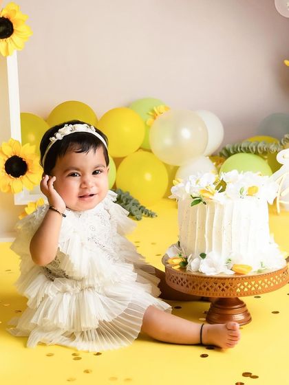 A picture perfect moment before the cake smash begins. This little girl looks so adorable in her frilly dress, surrounded by a cheerful yellow and sunflower theme.