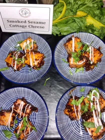 Our smoked sesame cottage cheese is a flavor-packed vegetarian option, drizzled with a creamy sauce and served on beautiful blue-and-white ceramic plates.
