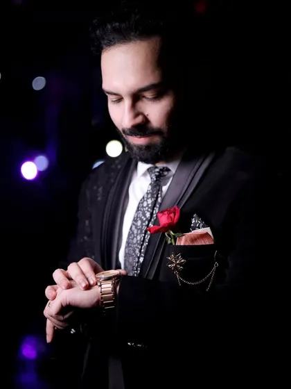 A close-up shot of the groom checking his watch, a classic and suave pose. The low-key lighting adds a touch of mystery and sophistication.