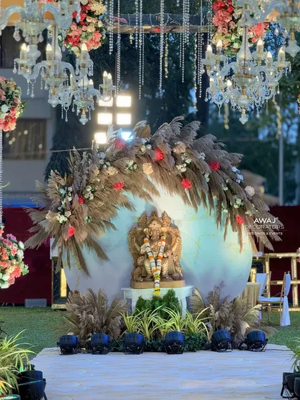 A sacred Ganesha installation at the entrance of an outdoor wedding, beautifully decorated with pampas grass, florals, and chandeliers to welcome guests with blessings.