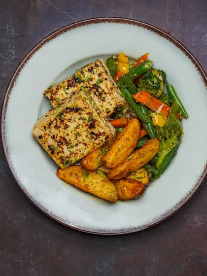 Another angle of the grilled paneer platter, showing the texture of the seasoned paneer and roasted vegetables. The dark, dramatic styling is consistent and professional.