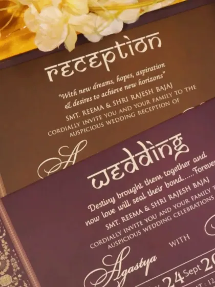 A close-up of wedding and reception inserts in deep purple and brown, with elegant script that complements a regal invitation.