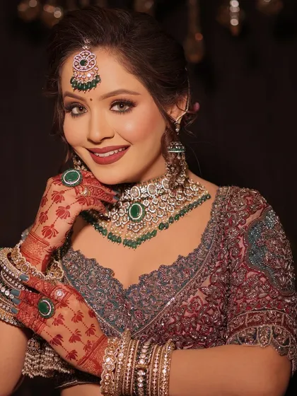 A beautiful heritage bride with stunning green jewelry that perfectly complements the rich, red tones of her mehndi.
