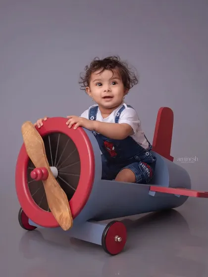 Let your child's imagination take flight with a creative pilot-themed photoshoot. This little aviator is ready for adventure, sitting inside a custom-made wooden airplane prop in my Kolhapur studio.