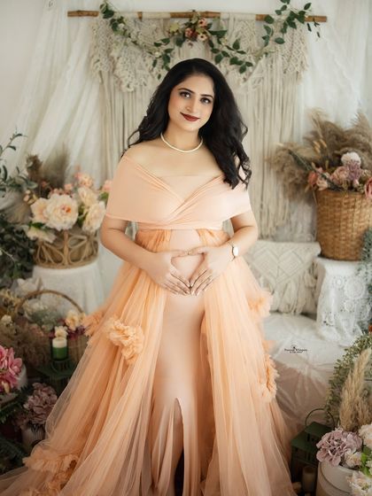 A stunning solo portrait of a mother-to-be in a delicate peach gown. The floral details on the dress add a touch of whimsical romance.