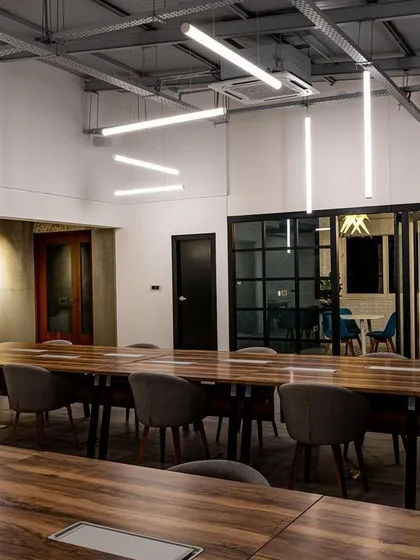 A different perspective of the sculptural lighting installation. Notice how the light is bright enough for tasks but diffused to prevent harsh shadows or glare on screens, which is crucial for a comfortable working environment.
