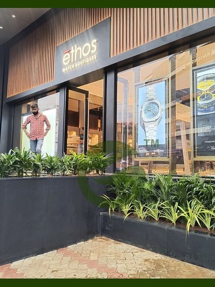 The completed entrance for the Ethos Watch Boutique. The dark planters and vibrant green plants provide a beautiful contrast against the building's modern architecture, enhancing its curb appeal.