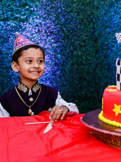 A candid shot of the birthday boy, smiling as he gets ready to cut his race-car themed cake. These are the moments families will cherish.