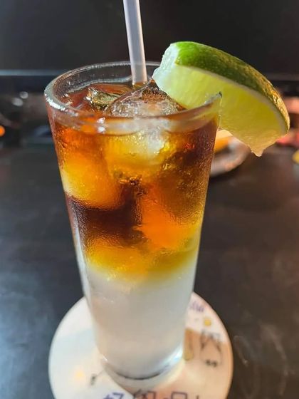A tall and refreshing Long Island Iced Tea. This popular cocktail is served in a highball glass with a lime wedge, perfect for an evening party.