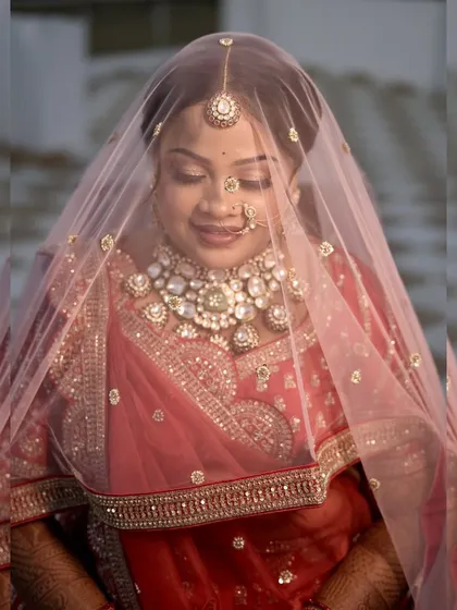 A classic pose with the veil covering her face, exuding timeless bridal grace. The makeup shines through beautifully.