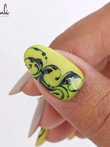 A close-up of a single nail with the neon yellow and black swirl design.