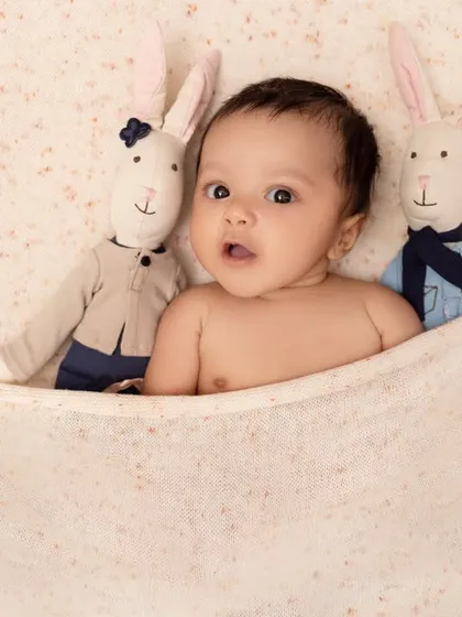 Peeking out from under the covers with his favorite bunny friends. This simple and sweet shot captures the quiet, curious moments of early babyhood.