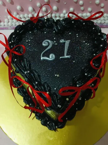 A glamorous heart-shaped cake for a 21st birthday. The black glitter finish and red ribbons make it a show-stopping centerpiece.