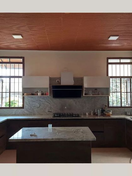 A modern kitchen with a terracotta filler slab ceiling, marble countertops, and large windows for ample natural light.