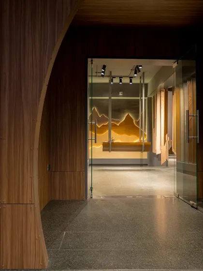 The entrance to the showroom is designed to be dramatic and inviting, with a curved wooden archway framing the view of the artistic installations within.