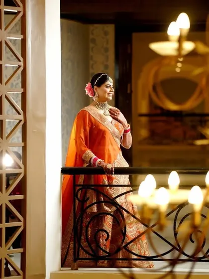 An elegant bridal portrait on a balcony, with a chandelier in the foreground creating a beautiful frame.