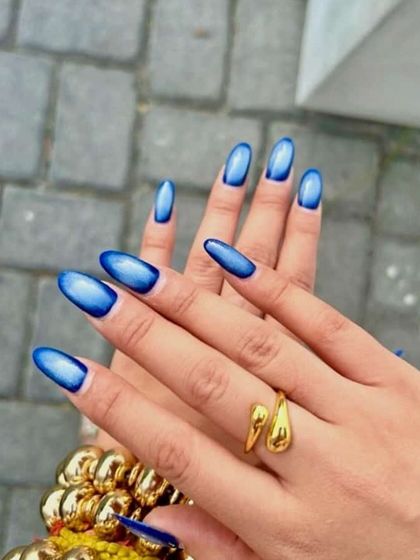 A vibrant blue aura or cat eye effect on long almond nails. The deep blue edges fade into a bright, glowing center for a mesmerizing look.