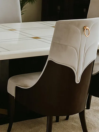 A close-up of the dining chair, revealing the leaf-like stitching on the back and the elegant metal ring pull. These small details are what elevate the design and add a touch of luxury.