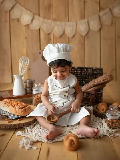 Our little baker exploring the props. I use real, safe items like wooden spoons and bread to make the experience authentic and fun for the kids.