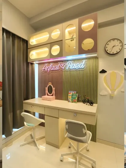 The shared study desk in the travel-themed room is designed for two. It features personalized neon signs, unique overhead storage with illuminated, capsule-shaped niches, and fun decor like a soccer ball clock.