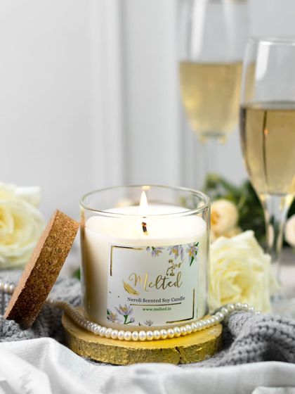 Capturing a brand's promise of everyday luxury. This lit candle is styled with pearls, white roses, and champagne, creating an elegant and celebratory scene that feels both cozy and sophisticated.