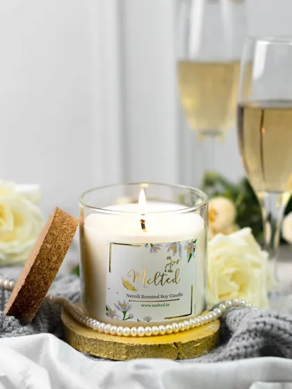 Capturing a brand's promise of everyday luxury. This lit candle is styled with pearls, white roses, and champagne, creating an elegant and celebratory scene that feels both cozy and sophisticated.