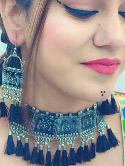 A close-up focusing on the model's expressive makeup and the detailed design of the oxidized jewellery.