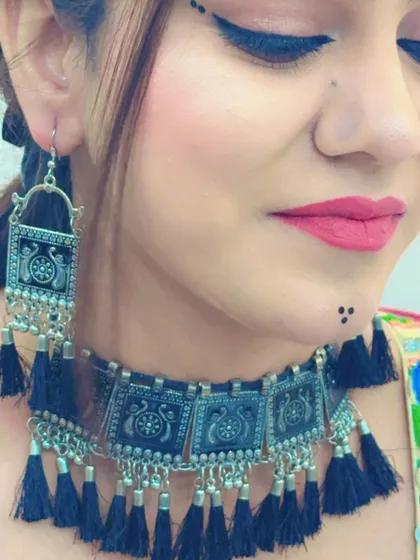 A close-up focusing on the model's expressive makeup and the detailed design of the oxidized jewellery.