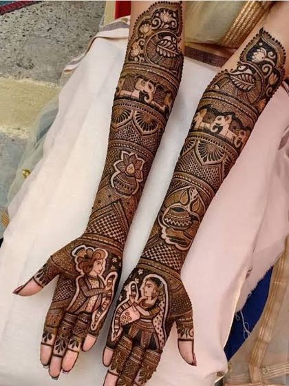 A full-arm bridal design rich with traditional Indian motifs, including elephants, peacocks, lotuses, and a charming bride and groom portrait on the palms.