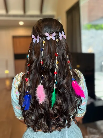 A minimalist and dreamy hairstyle for my bride's haldi. Soft waves are decorated with colorful feathers and butterfly clips for a fun, bohemian vibe.