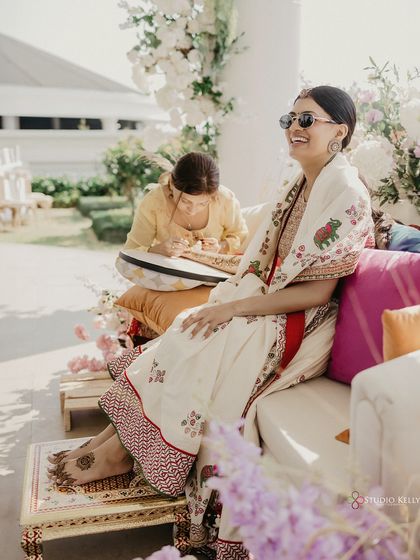 The bride relaxes and smiles as her Mehendi is applied, enjoying the sunny and beautiful atmosphere of her destination wedding in Vietnam.