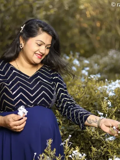 A candid moment of the mother-to-be interacting with nature. The soft light and her gentle smile create a serene and joyful portrait, celebrating the beauty of pregnancy.