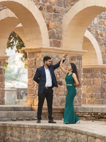 A playful moment as a couple dances on a historic stone structure during their pre-wedding shoot.