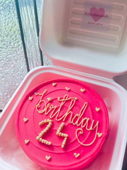 A vibrant pink bento cake for a 25th birthday. The swirling text and tiny hearts make it a fun and celebratory design.