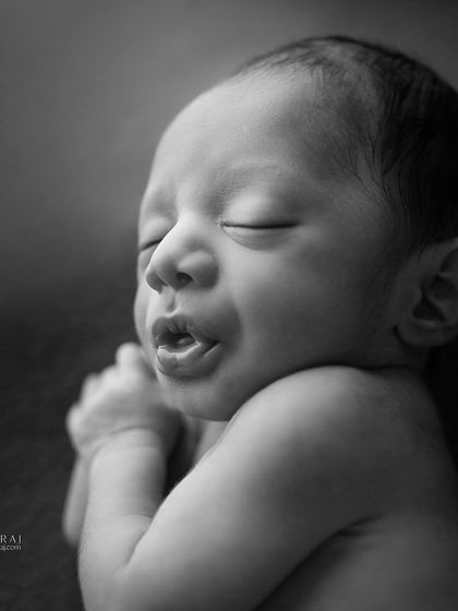 A newborn yawns, captured in dramatic black and white. This simple, unposed moment is full of character and life.