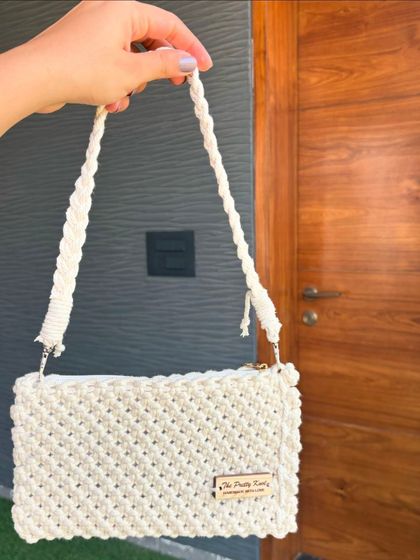 Our classic macrame handbag in a beautiful off-white color. It's a versatile piece that can be dressed up or down, and yes, we ship our products worldwide.