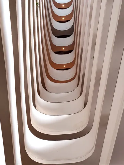 This abstract view shows the rhythmic pattern of the balconies overlooking the central courtyard at the Surat Diamond Bourse. The flowing, organic forms create a sense of movement and connection between the different levels of the world's largest office building.