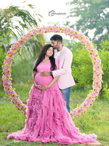 An intimate couple's portrait in front of a circular floral prop. The affection and joy are palpable in this beautiful outdoor shot.