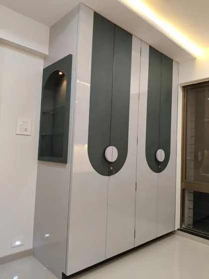 A unique wardrobe design with curved, two-tone panels and circular handles. An open niche with a spotlight is included for displaying a special item.