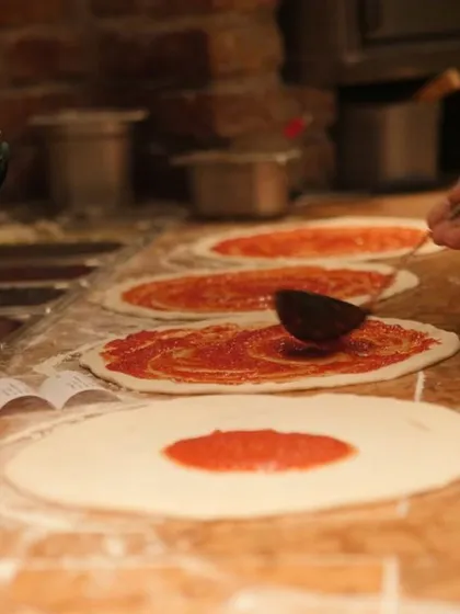 It all starts with the sauce. I spread my rich, tangy tomato sauce over hand-stretched dough, getting the base ready for some serious toppings. This is pizza done right.