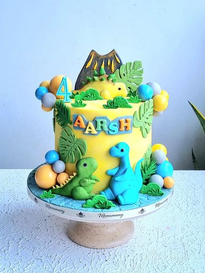 A full view of the yellow dinosaur cake with the volcano topper.