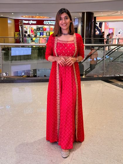 A stunning red gown-style Indian outfit with a jacket, ideal for making a grand entrance at a wedding or Diwali party.