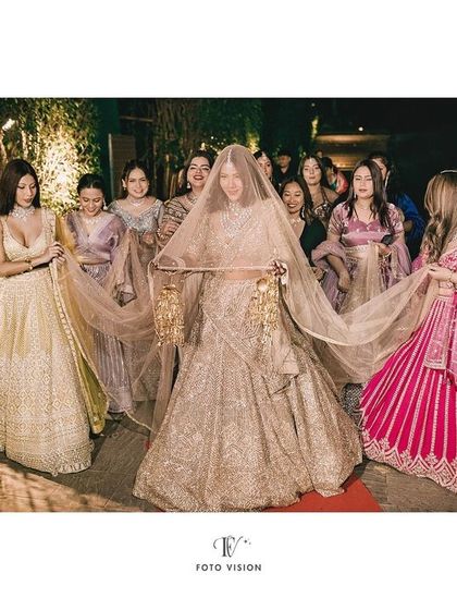 The bride's entrance, surrounded by her bridesmaids. We capture the 'phoolon ki chadar' moment, focusing on the bride's serene expression as she walks towards her future.